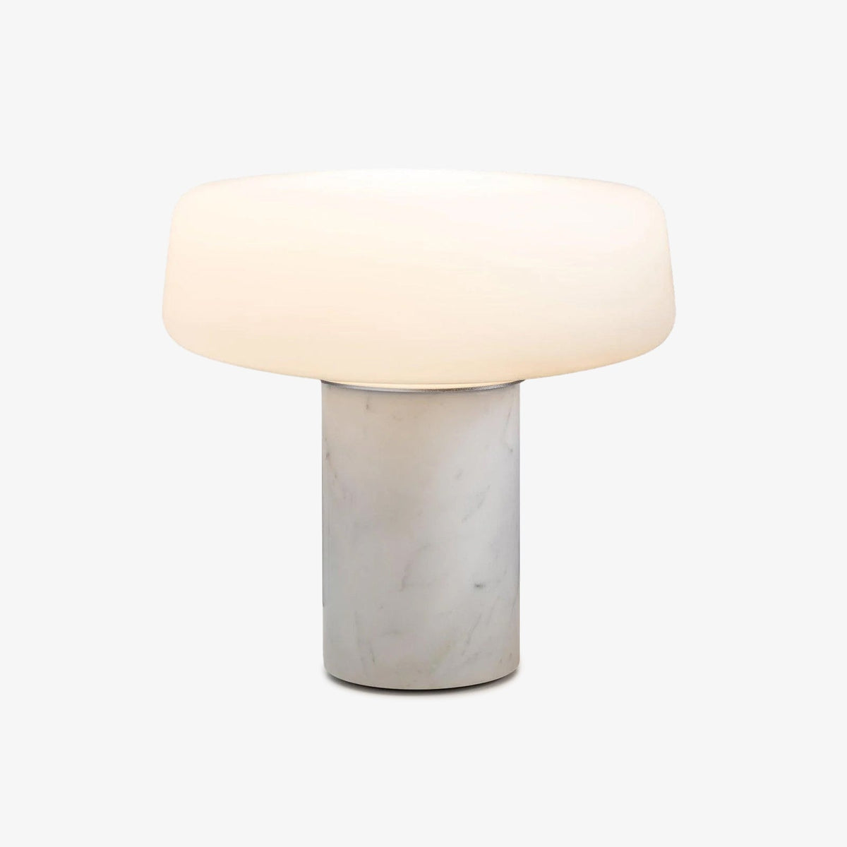 White marble Clérachic table lamp with its frosted glass dome shade shown on a plain grey studio background, unlit.