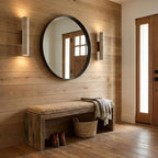 A round mirror and entry bench sit between two of this Clérachic wall light, lit, on a planked wall.