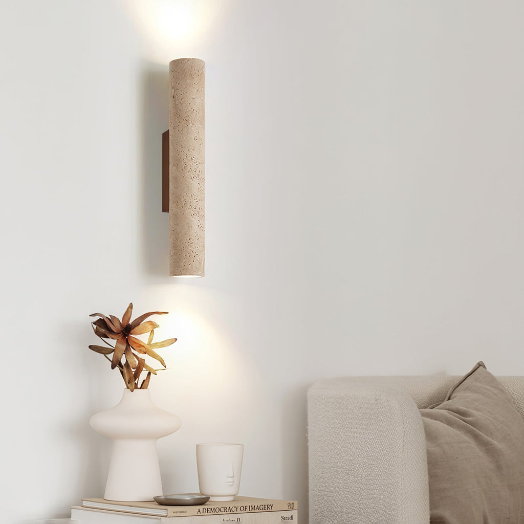 A sculptural vase and candle sit on a console below this Clérachic wall light, lit, against a white wall.