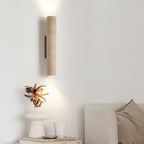 A sculptural vase and candle sit on a console below this Clérachic wall light, lit, against a white wall.