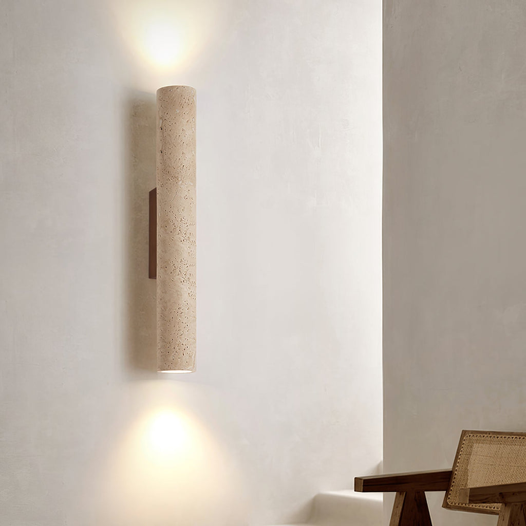 This Clérachic wall light glows lit above a rattan table on a softly textured plaster wall.