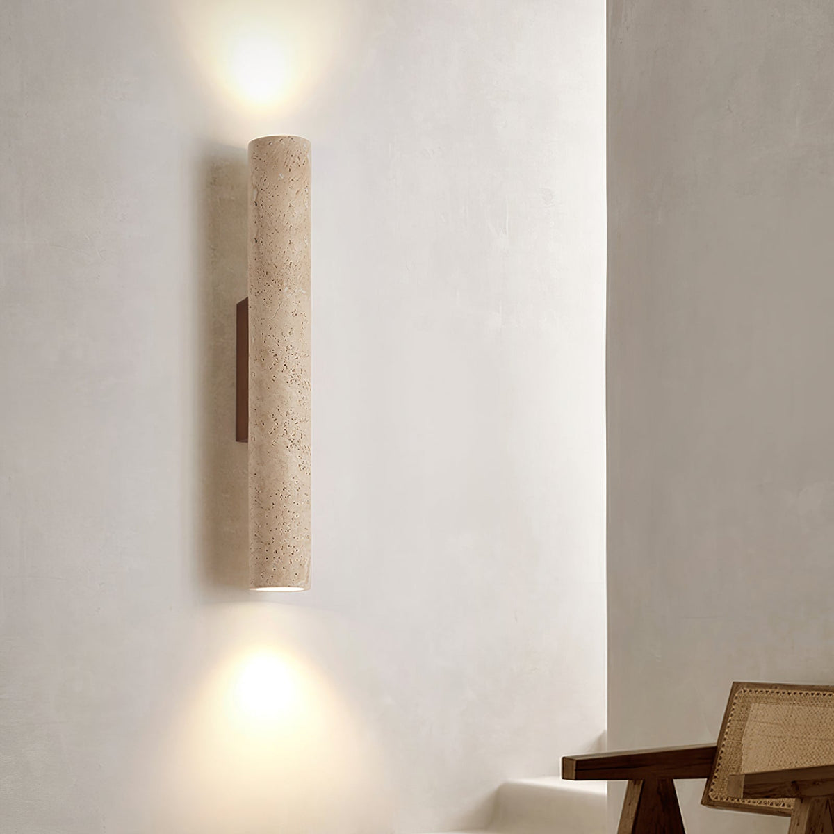 This Clérachic wall light glows lit above a rattan table on a softly textured plaster wall.