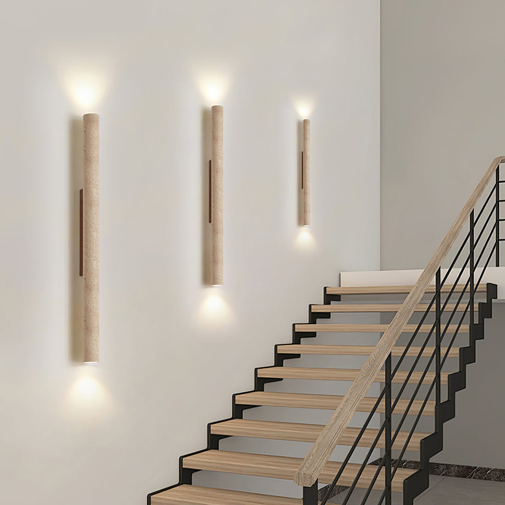 Three of this Clérachic wall light run lit up a staircase wall beside wood and metal steps.