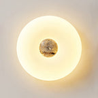 Close-up of a lit Clérachic ceiling light with a dark, marbled stone centre glowing warmly against a plain wall.