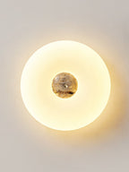 Clérachic ceiling light in a tall crop against a plain wall, its dark grey marbled stone centre lit warmly.