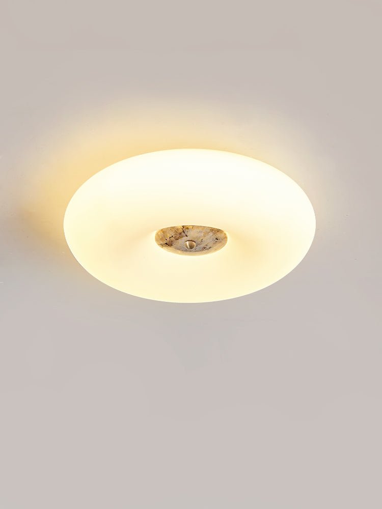 Clérachic ceiling light in an oval low-angle crop, a light grey stone centre glowing against the wall behind.