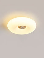 Clérachic ceiling light in an oval low-angle crop, a light grey stone centre glowing against the wall behind.
