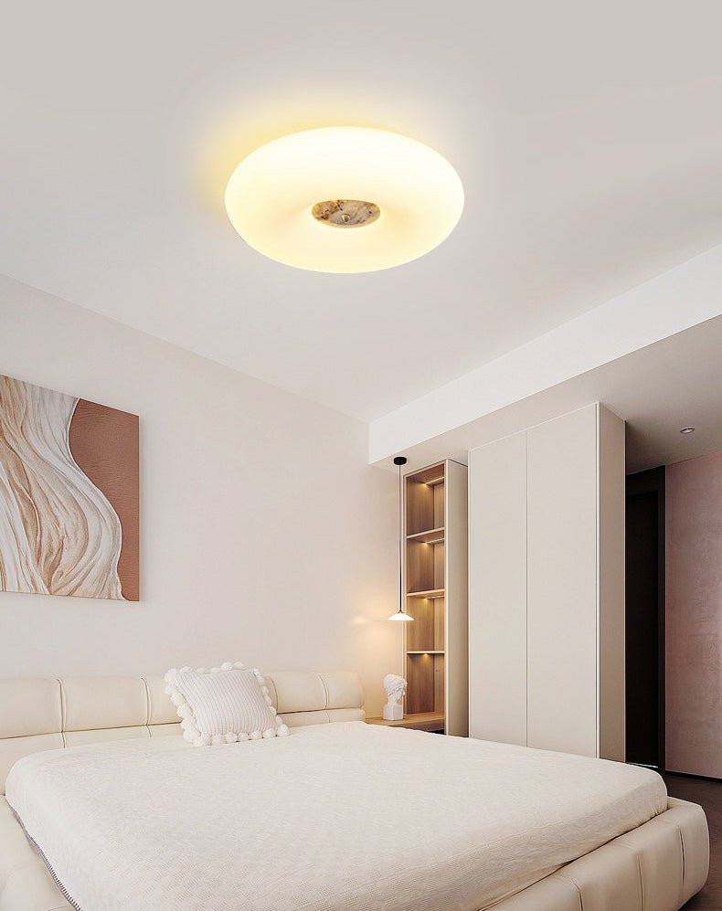 Clérachic ceiling light mounted in a bright bedroom corner, lit above a cream leather bed and bookshelf display.
