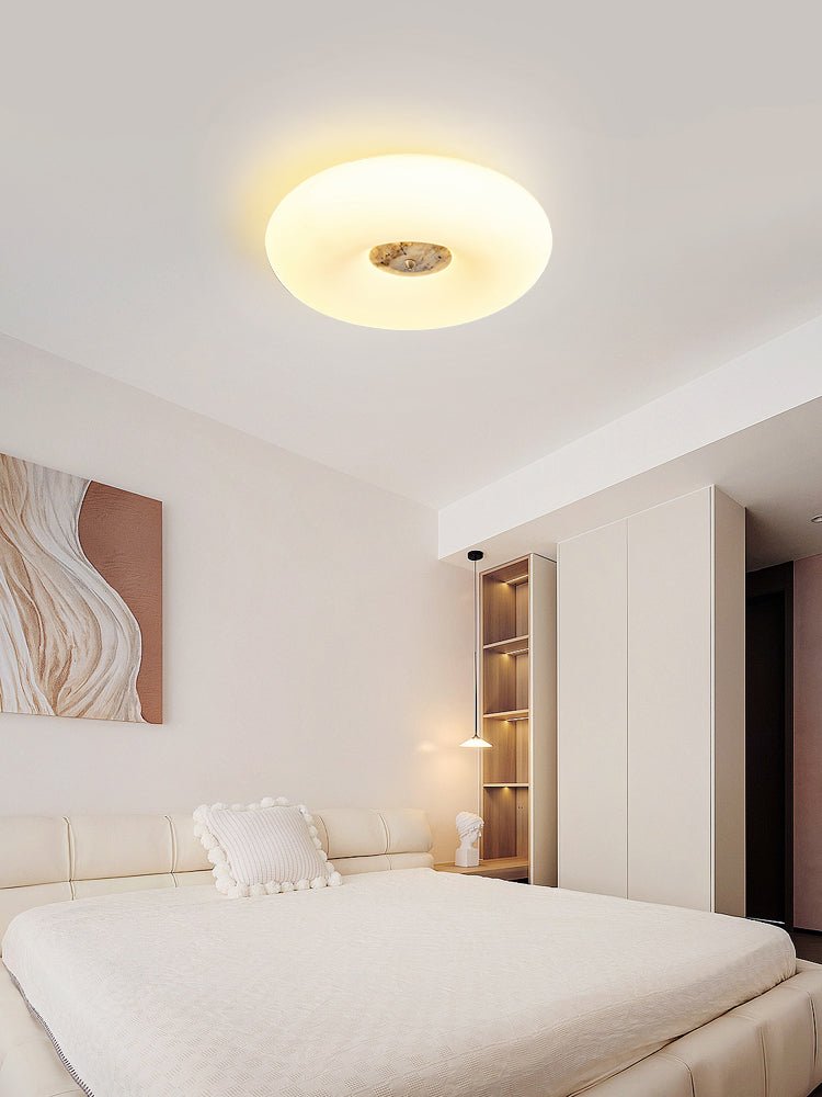 Clérachic ceiling light in the same cream bedroom, a closer crop showing the bookshelf and its glow more clearly.