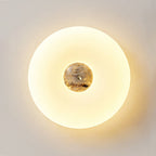 Extreme close-up of a lit Clérachic ceiling light, its dark brown stone centre and brass screw fitting clearly visible.