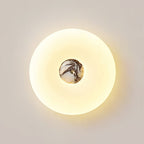 Extreme close-up of a lit Clérachic ceiling light, its black-and-white marbled stone centre and brass fitting visible.