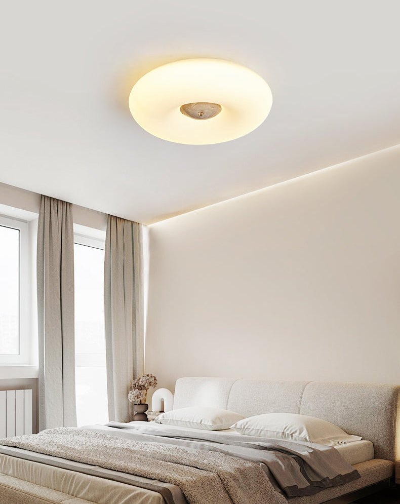 Clérachic ceiling light lit above a bedroom with dark curtains, a radiator, and dried flowers on the nightstand.