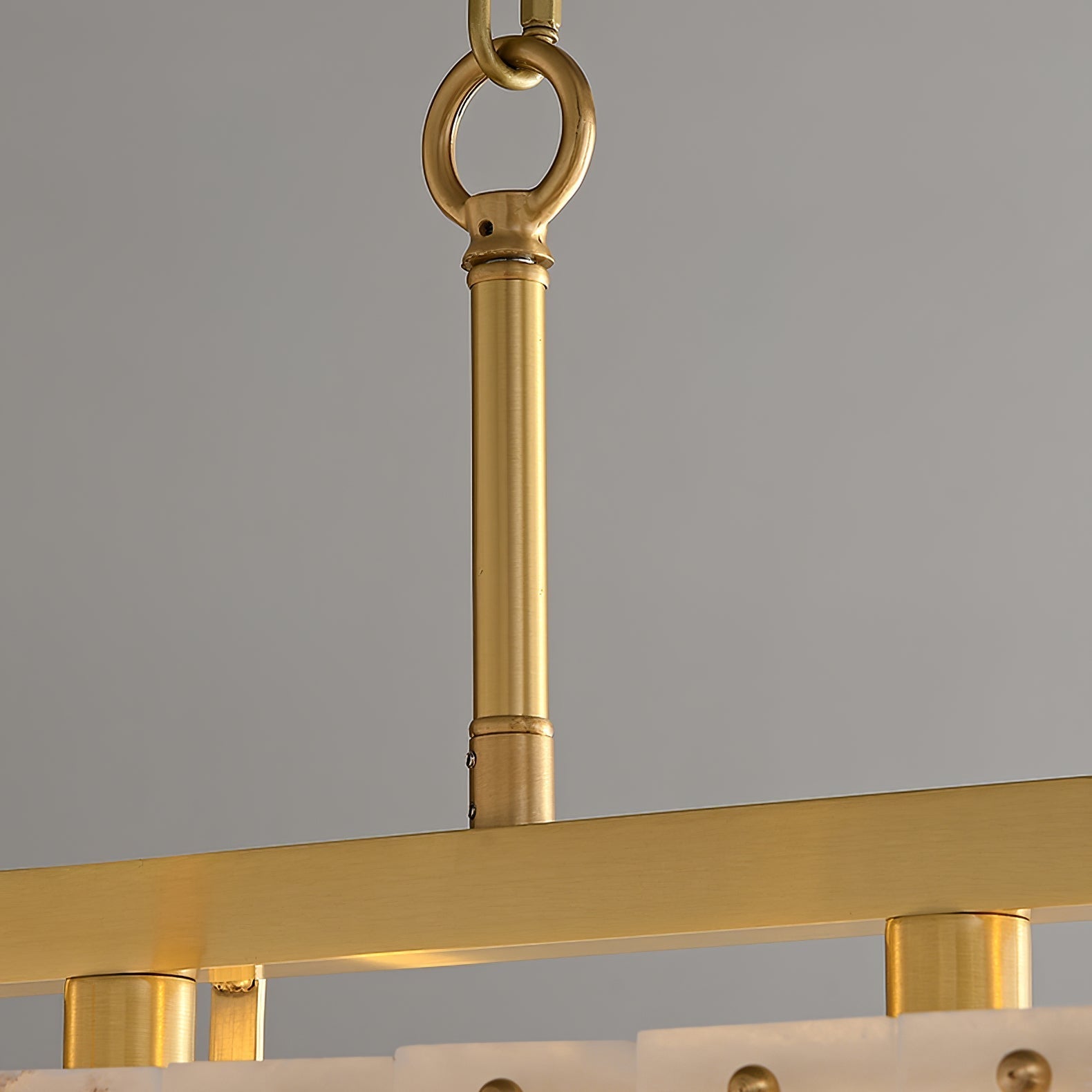 Close-up of the brass suspension rod, ring and chain above the chandelier's top rail.