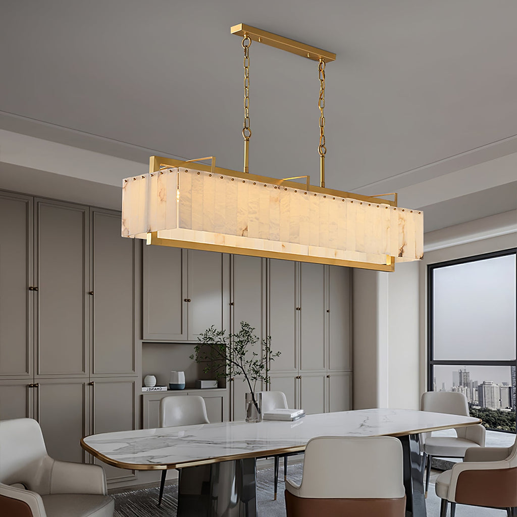 The chandelier lit over a dining table in a grey room, tall window and cabinetry behind.