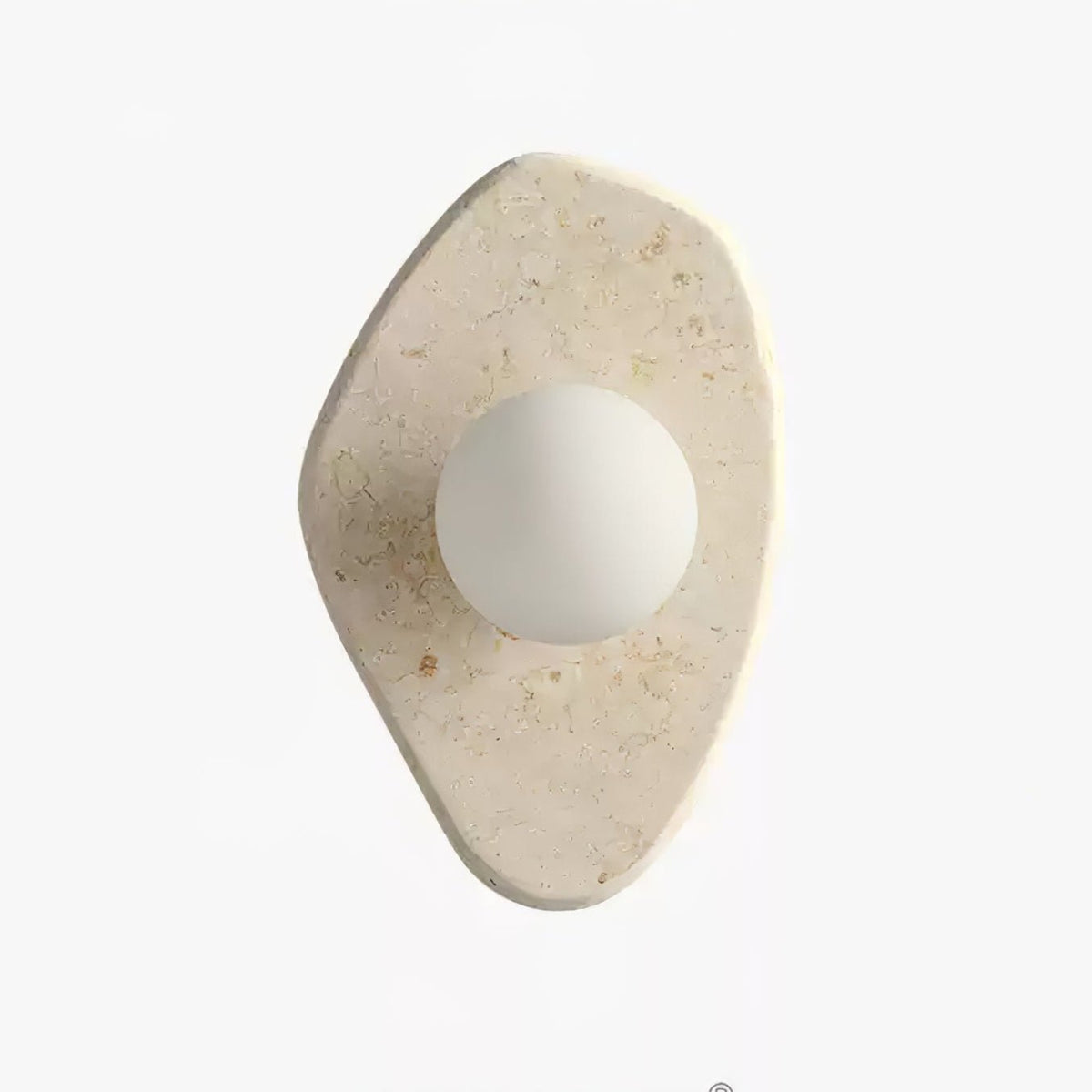 Unlit beige stone wall light from Clérachic on a white studio background, showing its freeform carved shape.