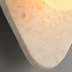 Close-up of the beige stone's rounded edge and mottled texture on this unlit Clérachic wall light.