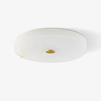 Unlit Olaean flush mount on white, brass centre cap and faint amber veining along the alabaster rim.