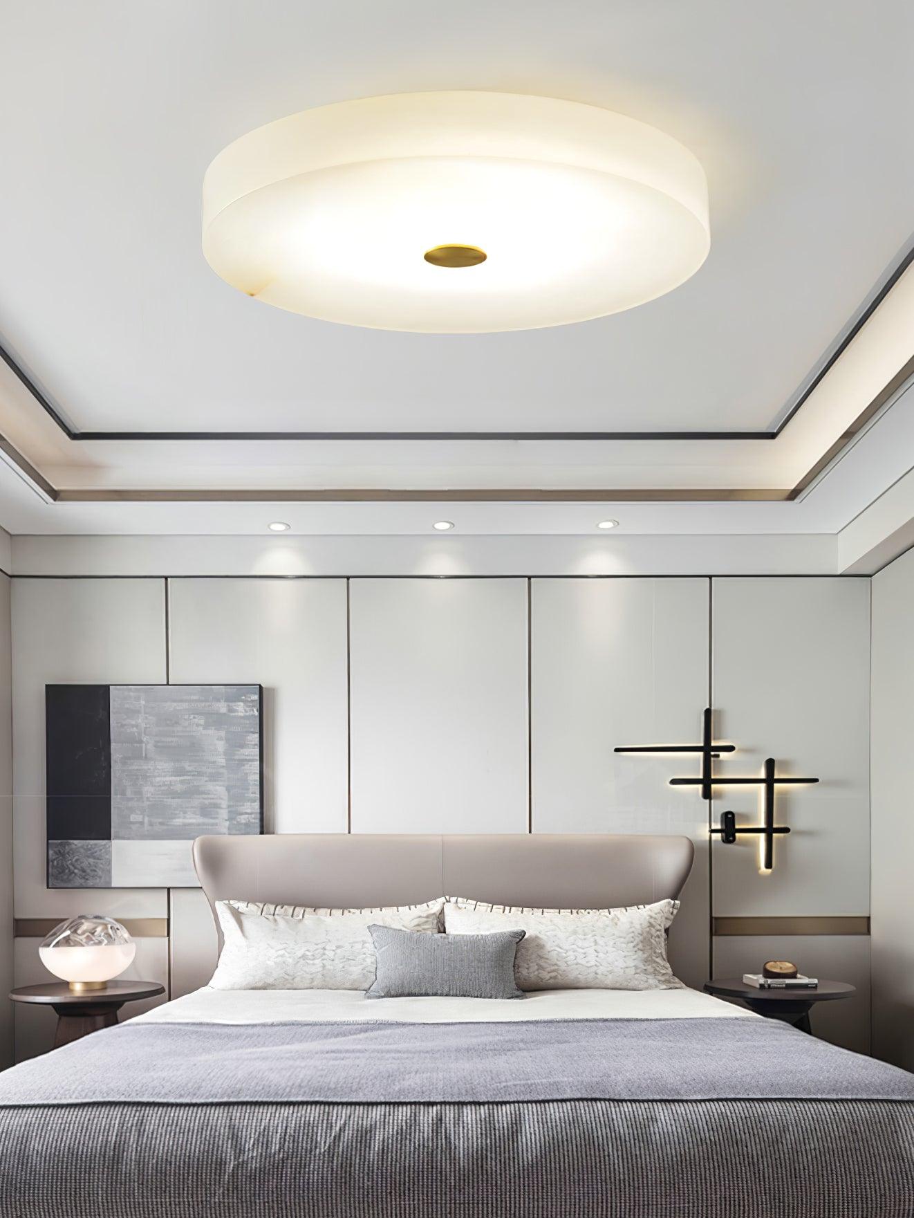 The Olaean flush mount lit above a bed, sitting flat against a recessed tray ceiling.