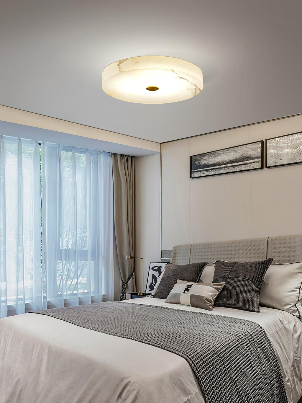 Olaean flush mount lit in a bedroom by a curtained window, veining in the alabaster clearly visible.