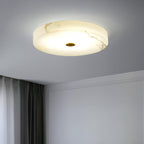 Olaean flush mount lit near a corniced wall, warm veins running across the alabaster shade.