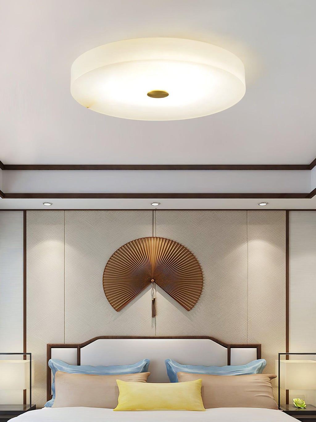 Olaean flush mount lit above a bed dressed in blue and yellow, a folding-fan artwork on the wall.