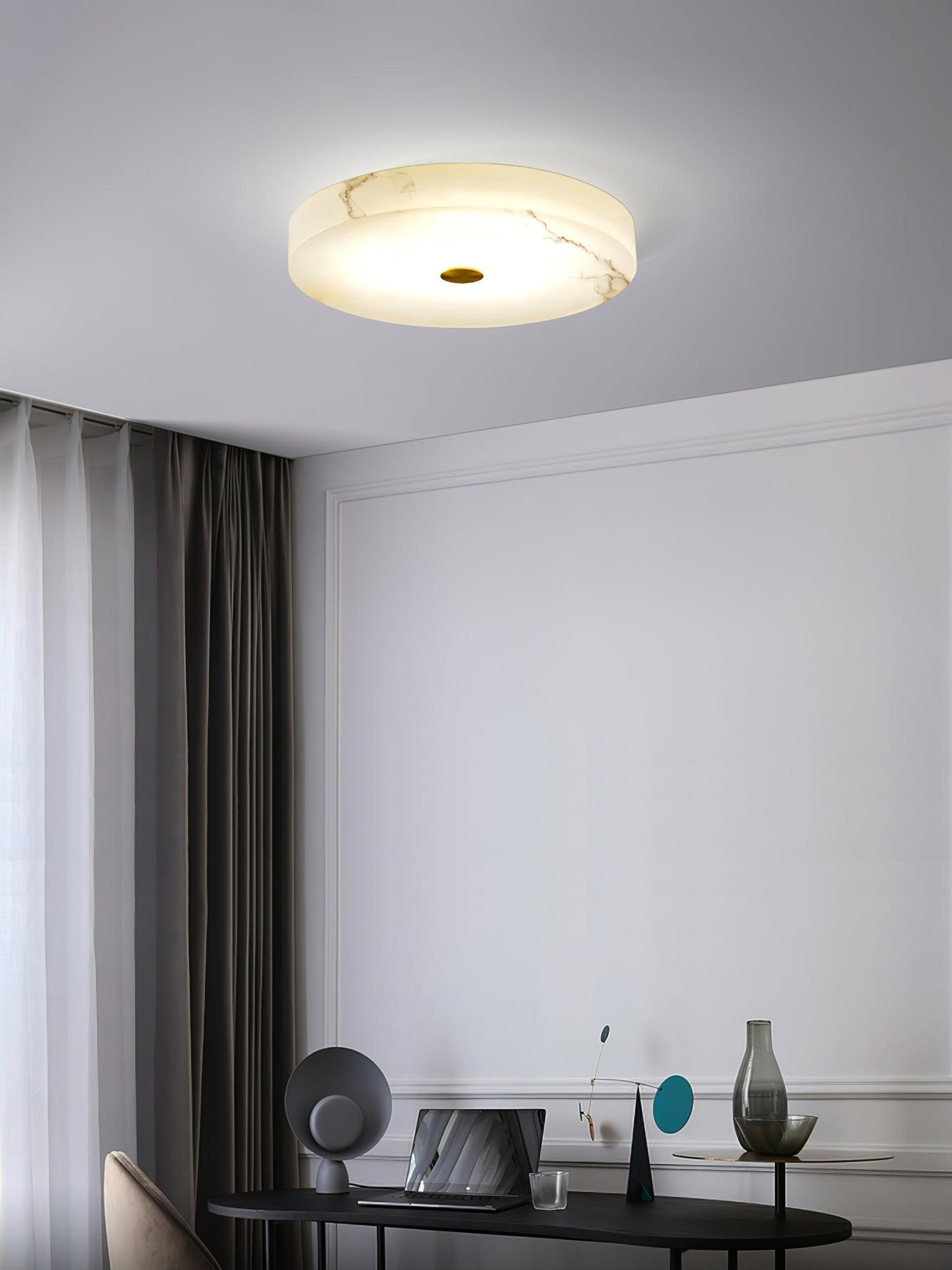 Olaean flush mount glowing above a work corner with a laptop, vase and dark curtains.