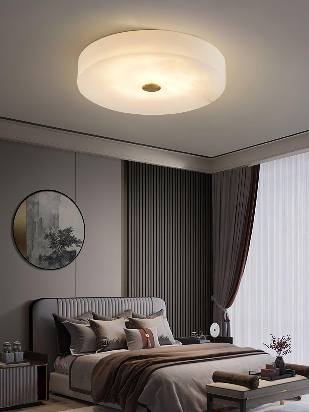 Large Olaean flush mount lit above a bed, round mirror and slatted wood panel on the wall behind.