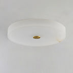 Unlit Olaean flush mount seen from below, brass cap flush with the flat alabaster underside.