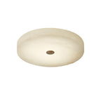 Product view of the unlit Olaean flush mount on white, showing the cream alabaster drum and brass cap.