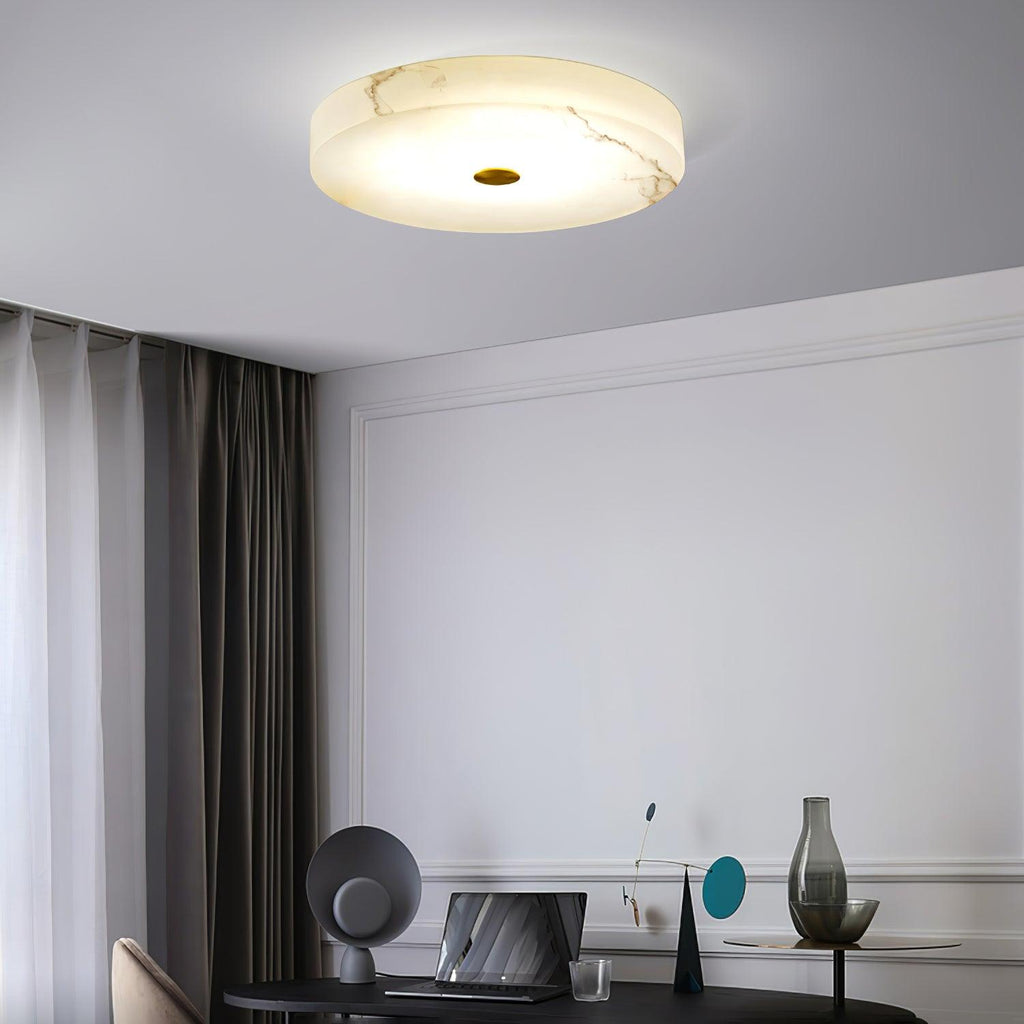 Olaean flush mount lit above a desk corner, veined alabaster glowing against a grey ceiling.