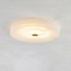 Olaean flush mount lit from a low angle, showing the stepped edge of the alabaster drum.