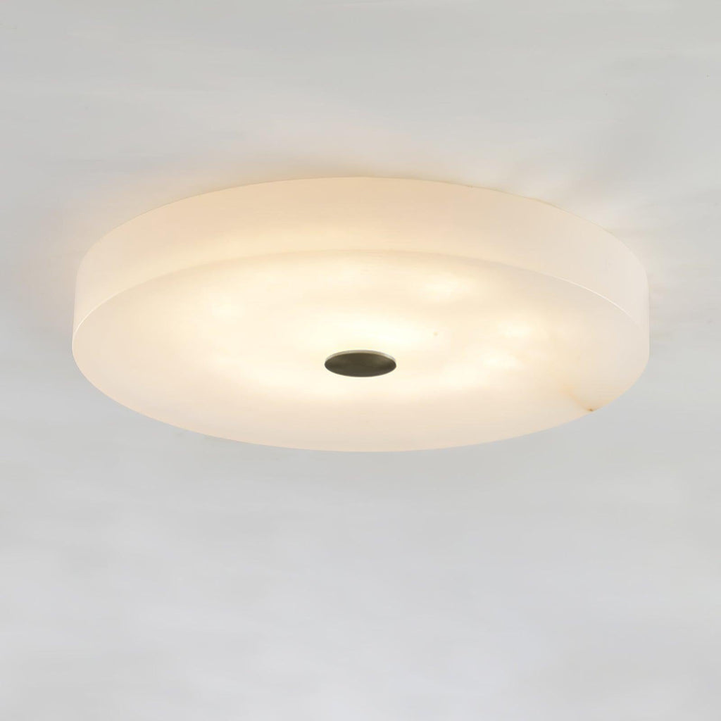 Olaean alabaster flush mount in the dark-cap version, lit softly and seen from below at an angle.