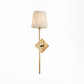 Lit on a plain white background, this Clérachic sconce's tall alabaster shade glows above its brushed brass diamond backplate.