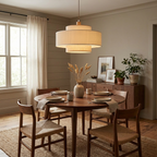 This Clérachic pendant hangs above a round dining table near tall windows dressed with sheer curtains.