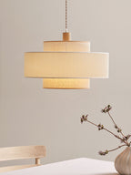 This Clérachic pendant hangs against a plain wall, a small dried branch in a vase on the wood surface below.