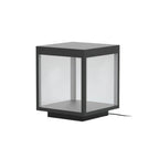 Stainless steel outdoor post light with warm glow on a patio