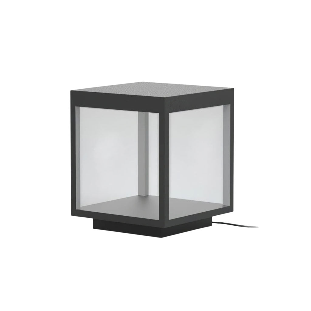 Stainless steel outdoor post light with warm glow on a patio