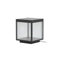 Square stainless steel outdoor post light glowing warmly in a garden