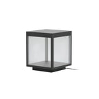 Square stainless steel outdoor post light glowing warmly in a garden