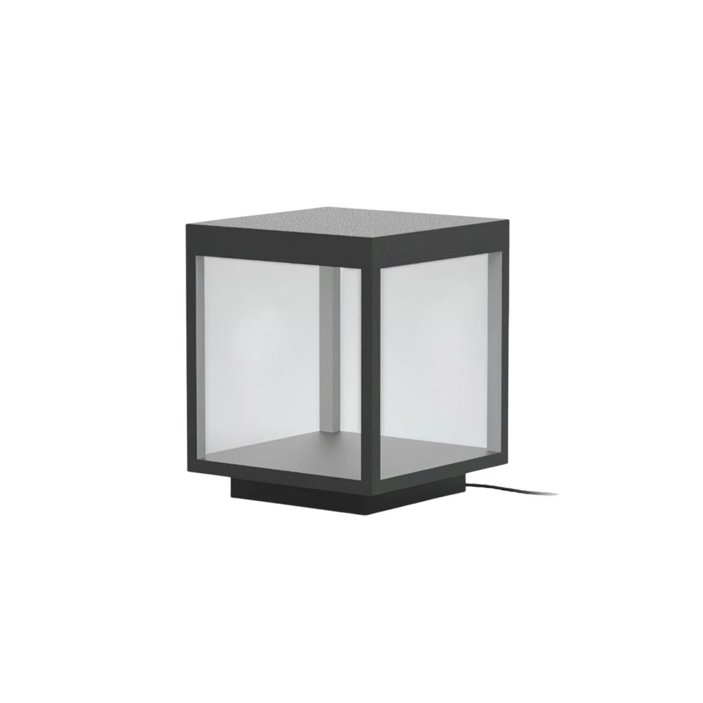 Square stainless steel outdoor post light glowing warmly in a garden