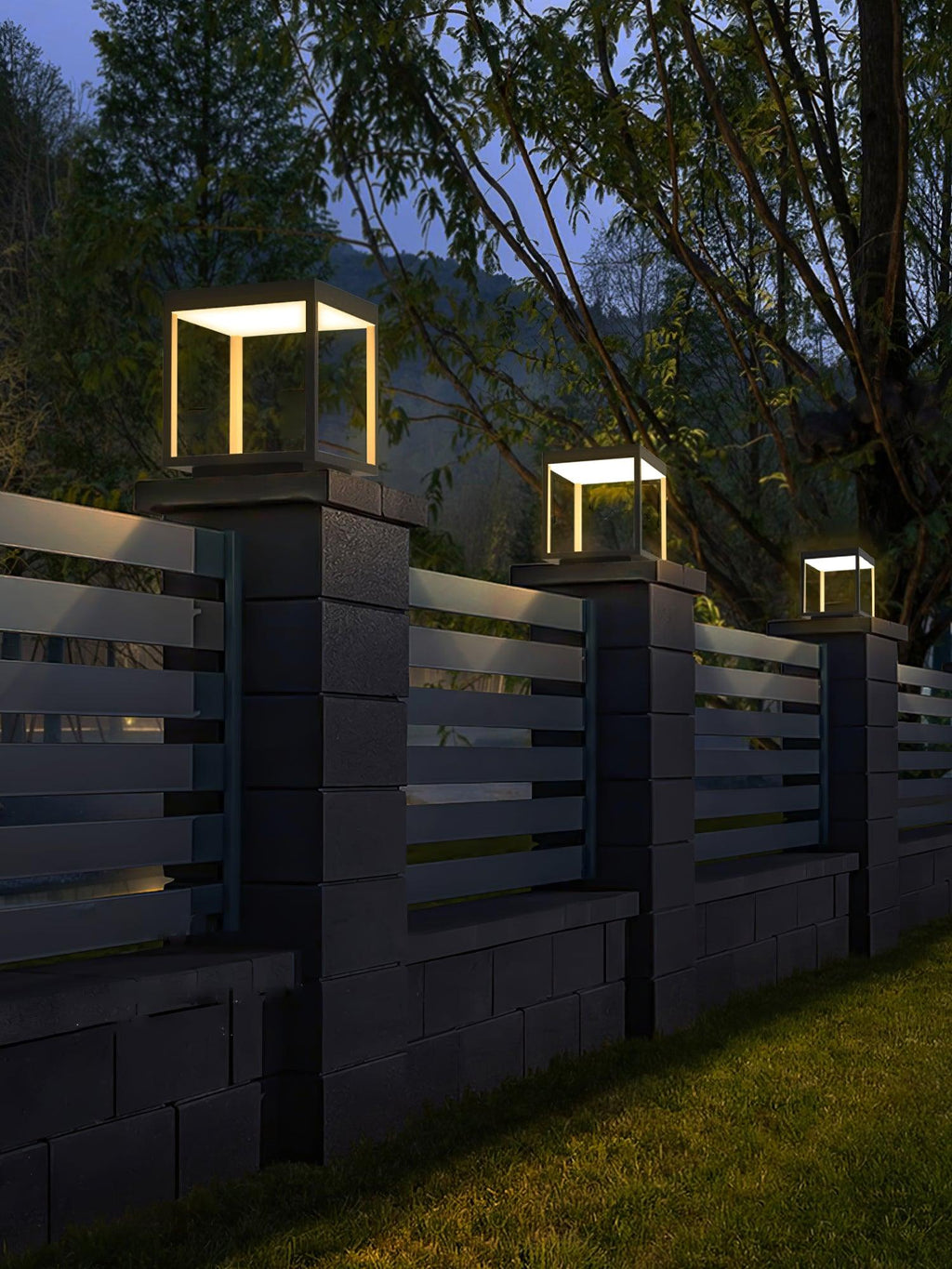 Outdoor post light with warm glow near a garden wall