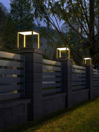 Outdoor post light with warm glow near a garden wall