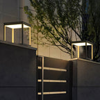 Square stainless steel outdoor light glowing along a path