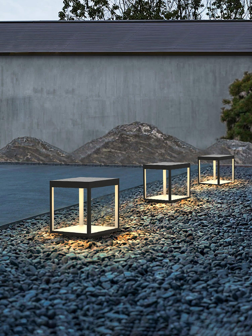 Square stainless steel outdoor light beside garden greenery