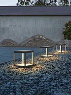 Square stainless steel outdoor light beside garden greenery