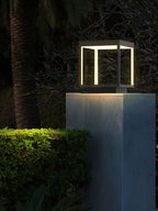 Outdoor post light glowing along a fence line at dusk