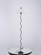 Squiggle floor lamp with dark fabric shade in a styled room