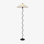 Squiggle floor lamp with fabric shade lit in a living space