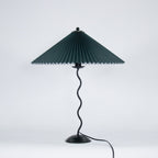 Squiggle table lamp glowing softly with pleated fabric shade