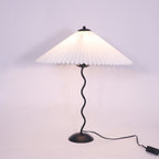 Squiggle table lamp lit on a side table with warm glow